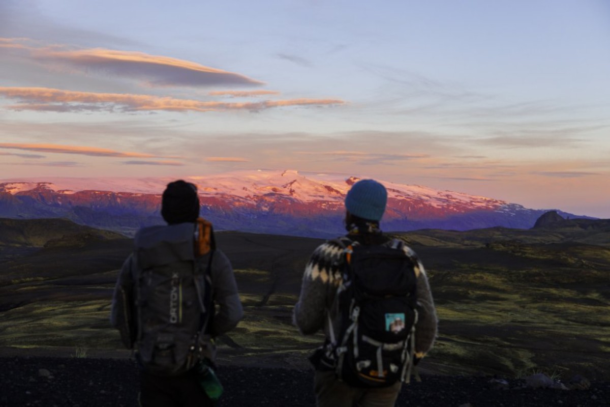 Two hikers with backpacks looking out over Icelandic highlands at sunset