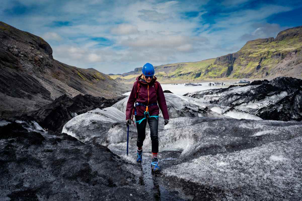Traveler wearing glacier hiking gear walking across black and white ice in Iceland